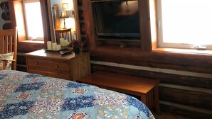 A bedroom with a bed, a dresser, a television, and a window.