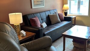 A living room with a leather sofa, a wooden coffee table, and a lamp.