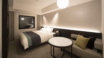 Une chambre d’hôtel avec un lit, une table de chevet, une lampe et une table ronde.