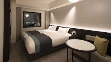 A modern hotel room with a large bed, bedside table, and a round table.