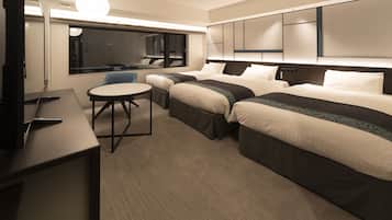 A hotel room with two beds, a desk, a chair, and a TV.