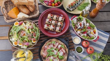 Variedad de platillos, incluyendo ensaladas, sándwiches y pescado a la parrilla sobre una mesa de madera.
