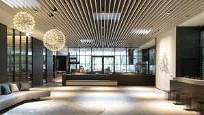 A spacious lobby with a modern design, featuring a curved sofa, a round rug, and a seating area with tables. - Hotel Vischio Osaka (Osaka)