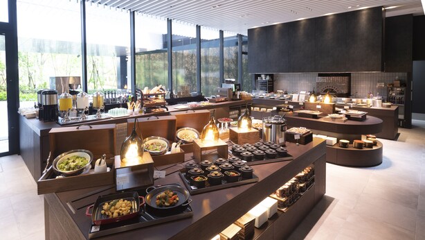 A modern buffet setup with various food stations and a kitchen area visible in the background. - Hotel Vischio Osaka (Osaka)
