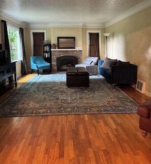 A living room with a fireplace, blue and grey sofas, a coffee table, and a patterned rug. - Wonderful home for couples, getaway with friends, families! (Olympia)