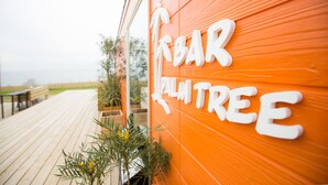 A wooden deck with a sign reading "BAR PALM TREE". - Grand Camping Palm Garden Maishima (Osaka)