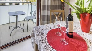 Un balcone con un tavolo apparecchiato per due persone, una bottiglia di vino e un vaso con fiori.