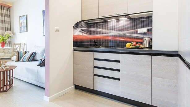 Una cucina moderna con piano di lavoro nero, pensili bianchi e una parete backsplash rossa.