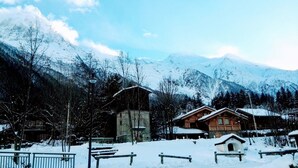 A wooden cabin with a stone tower, surrounded by snow-covered mountains and trees.