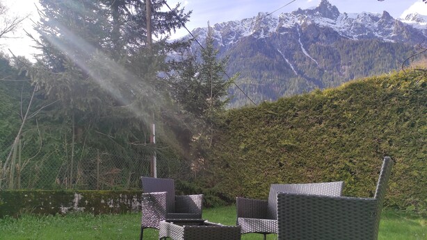 Outdoor wicker furniture in a grassy area with a mountain backdrop.