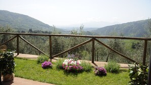 Un jardin avec une clôture en bois et des fleurs, donnant sur une vallée avec des collines.