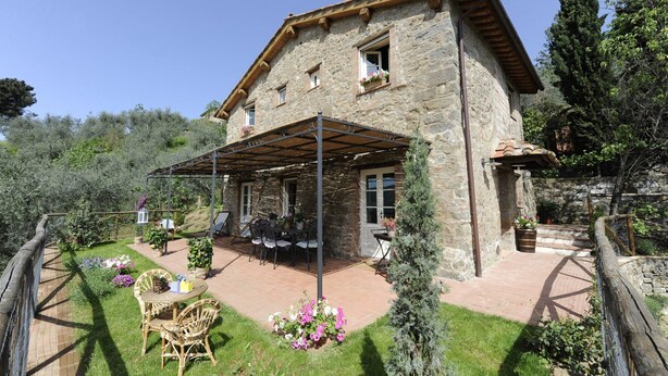Une maison en pierre dotée d’un patio couvert, d’un espace salon extérieur et d’un jardin.