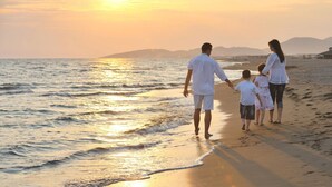 Une famille se promène sur une plage au coucher du soleil.