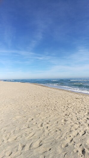 A wide sandy beach with gentle waves and a clear blue sky.