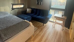 Ein Schlafzimmer mit einem Bett, einem blauen Sofa, einem kleinen Tisch und einem Fenster.