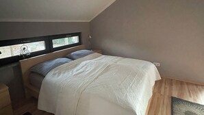 Ein Schlafzimmer mit einem Bett, einem Nachttisch, einem Fenster und einem Gemälde an der Wand.