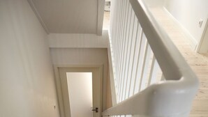 Una escalera de madera con barandillas blancas que lleva a una puerta en la parte superior.