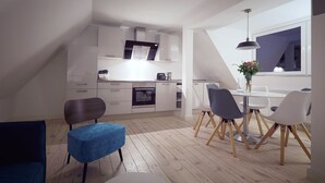 Una cocina moderna con armarios blancos, horno empotrado y zona de comedor con mesa y sillas redondas.