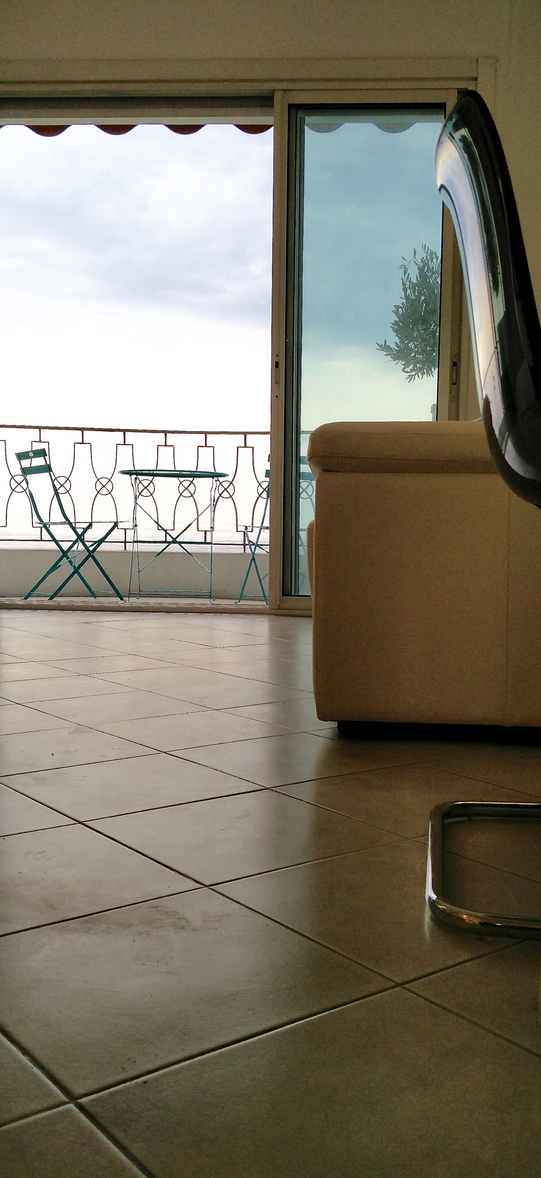 A balcony with a table and chairs, a sofa, and a sliding glass door.