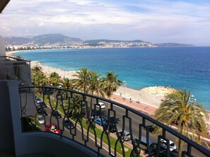 A balcony with a view of a beach, palm trees, and a coastal town in the background. - Promenade des Anglais, front Sea & Beach, Outstanding Panorama  (Nice)