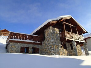 A stone building with a wooden balcony and snow-covered roof.