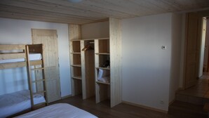 Une chambre avec deux lits superposés, une armoire en bois et un petit placard.