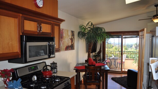 A kitchen with wooden cabinets, a microwave, a stove, and a dining area with a table and chairs.