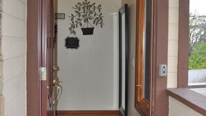 A hallway with a wooden door, a welcome sign, a potted plant, and a small rug.