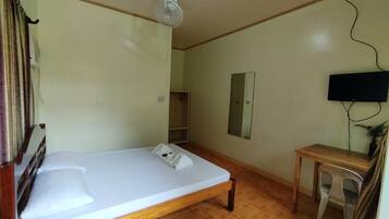 A room with a single bed, a desk, a chair, a television, and a ceiling fan.