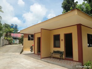 A yellow building with a red roof, a bench, and a motorcycle parked outside. - Replica Manor (Siquijor)