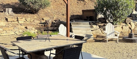 An outdoor patio with a pergola, stone table, and chairs.