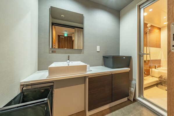 A modern bathroom with a white sink, dark wooden cabinets, and a glass shower enclosure.