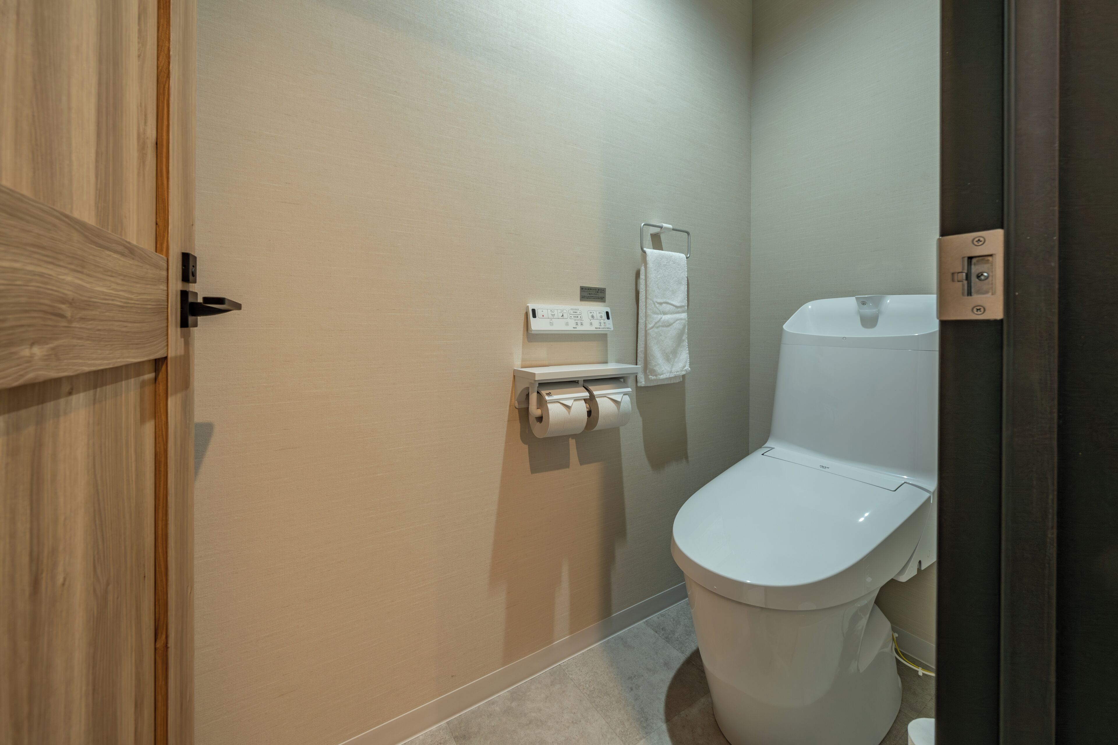 Un baño con inodoro, toallero y dispensador de toallas de papel.