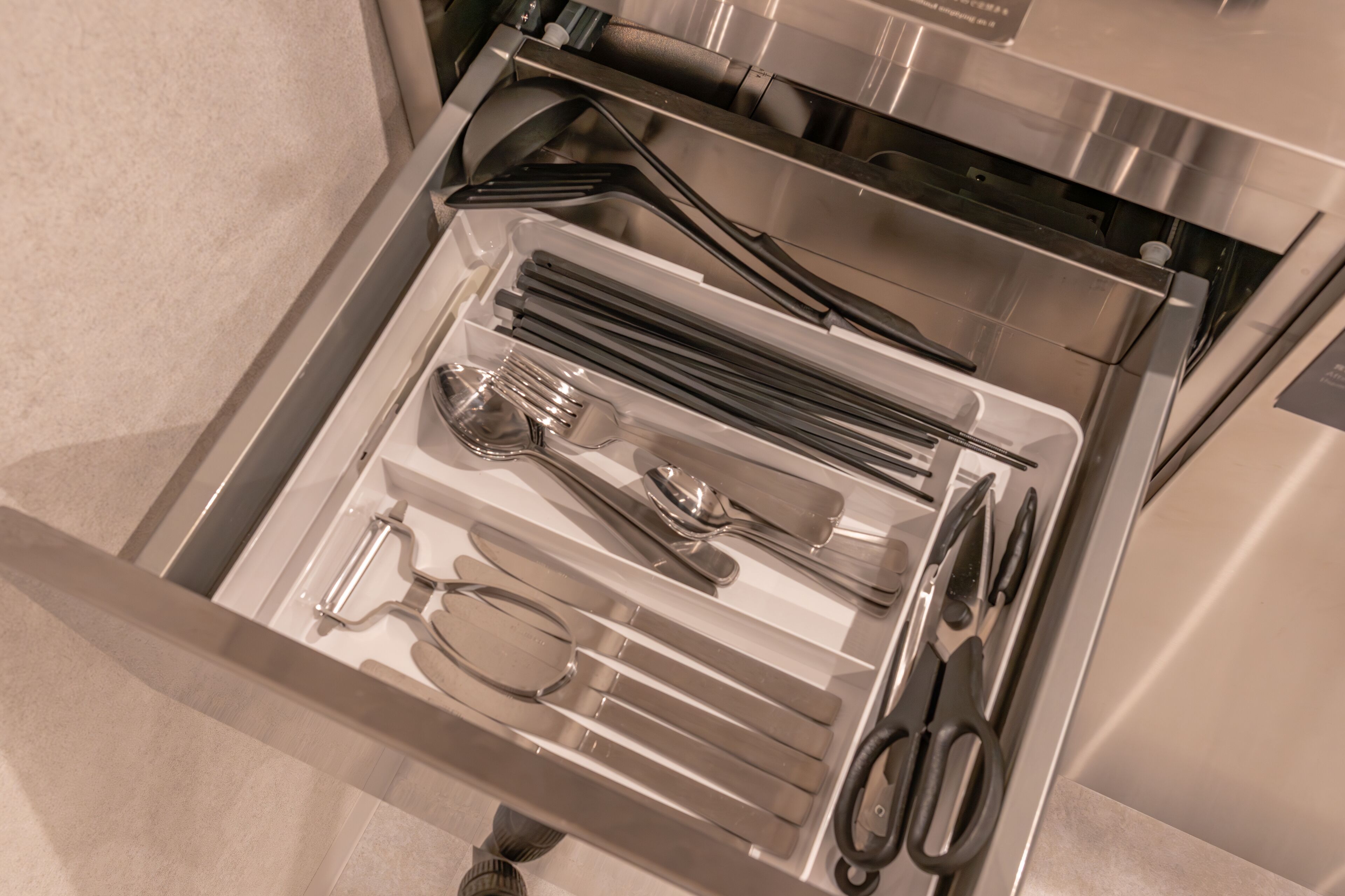 A drawer with utensils and glasses.