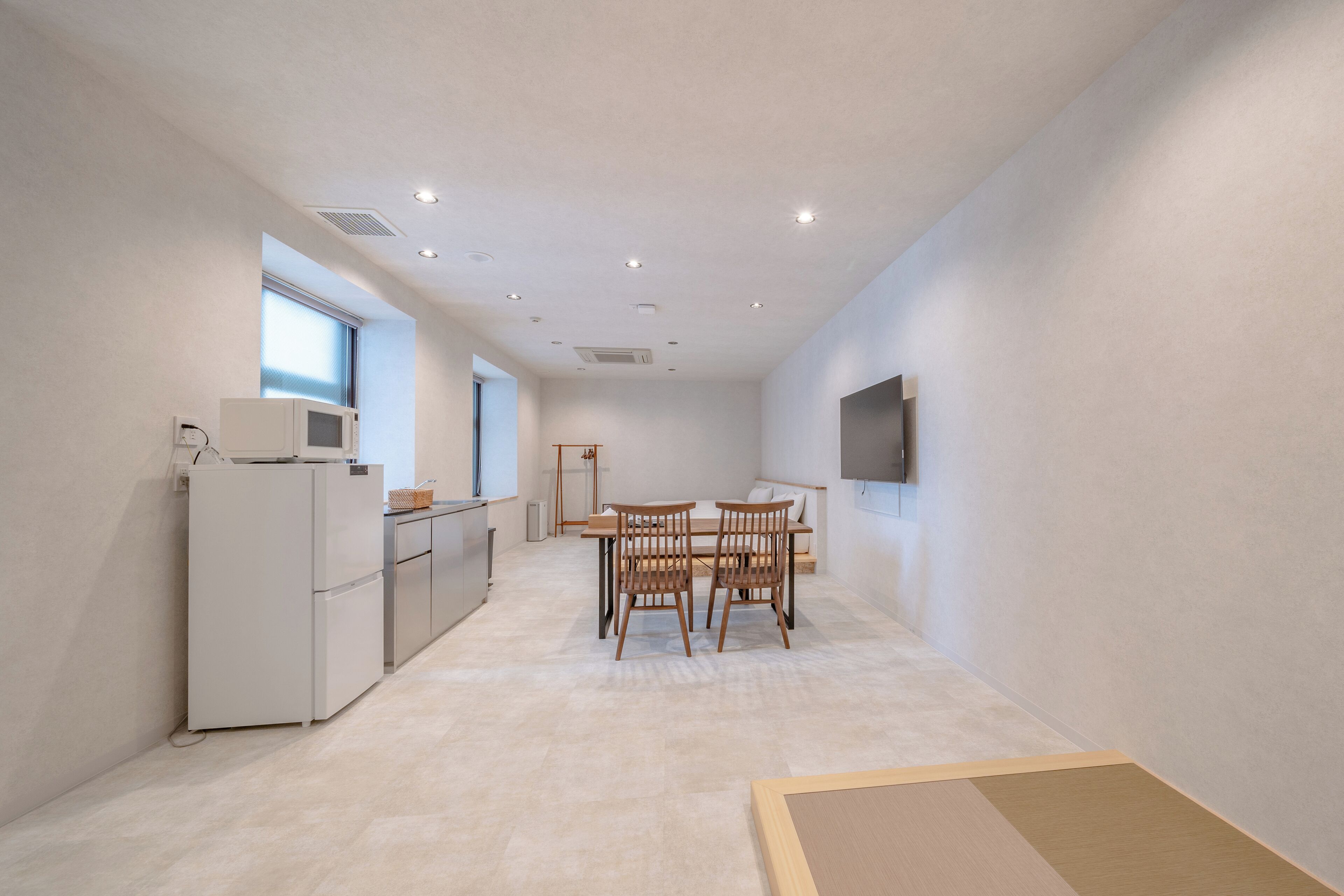 A modern kitchen with a refrigerator, microwave, and dining area with chairs and a table.