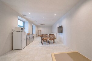 Una cocina moderna con refrigerador, microondas y comedor con sillas y una mesa.