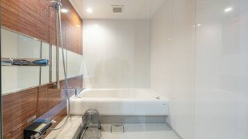 Un baño moderno con cabina de ducha de vidrio, bañera blanca y tocador empotrado con espejo.