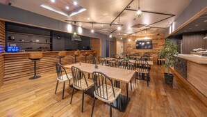 Un restaurant moderne avec un plancher en bois, des chaises en métal noir et une longue table en bois.