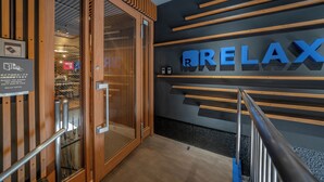 Un hall d'hôtel moderne, agrémenté d'une enseigne « RELAX », de touches de bois et d'une porte en verre donnant sur l'espace d'accueil.