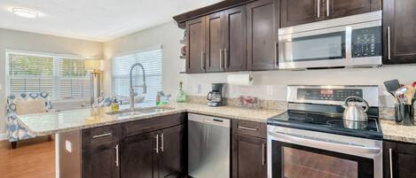 A modern kitchen with dark wood cabinets, stainless steel appliances, and a large island with a sink.