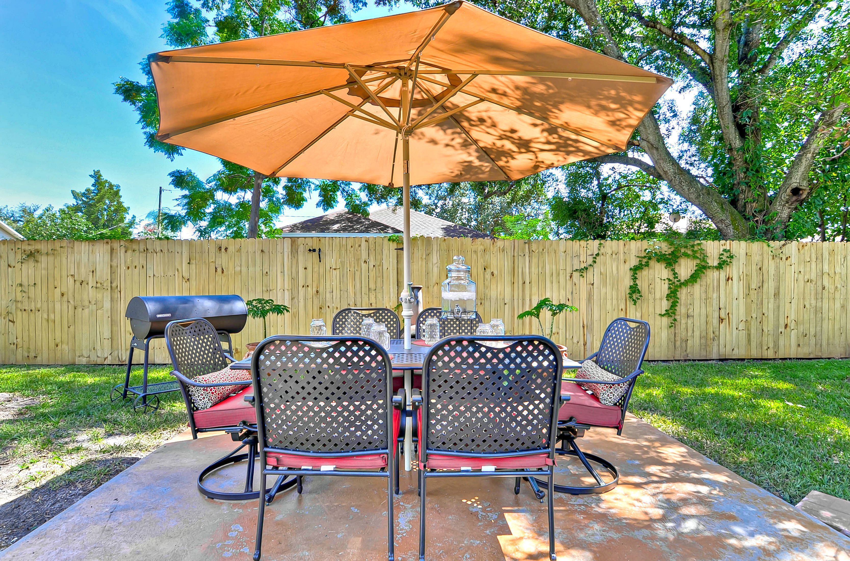 A patio with a table and chairs, a barbecue grill, and an umbrella.