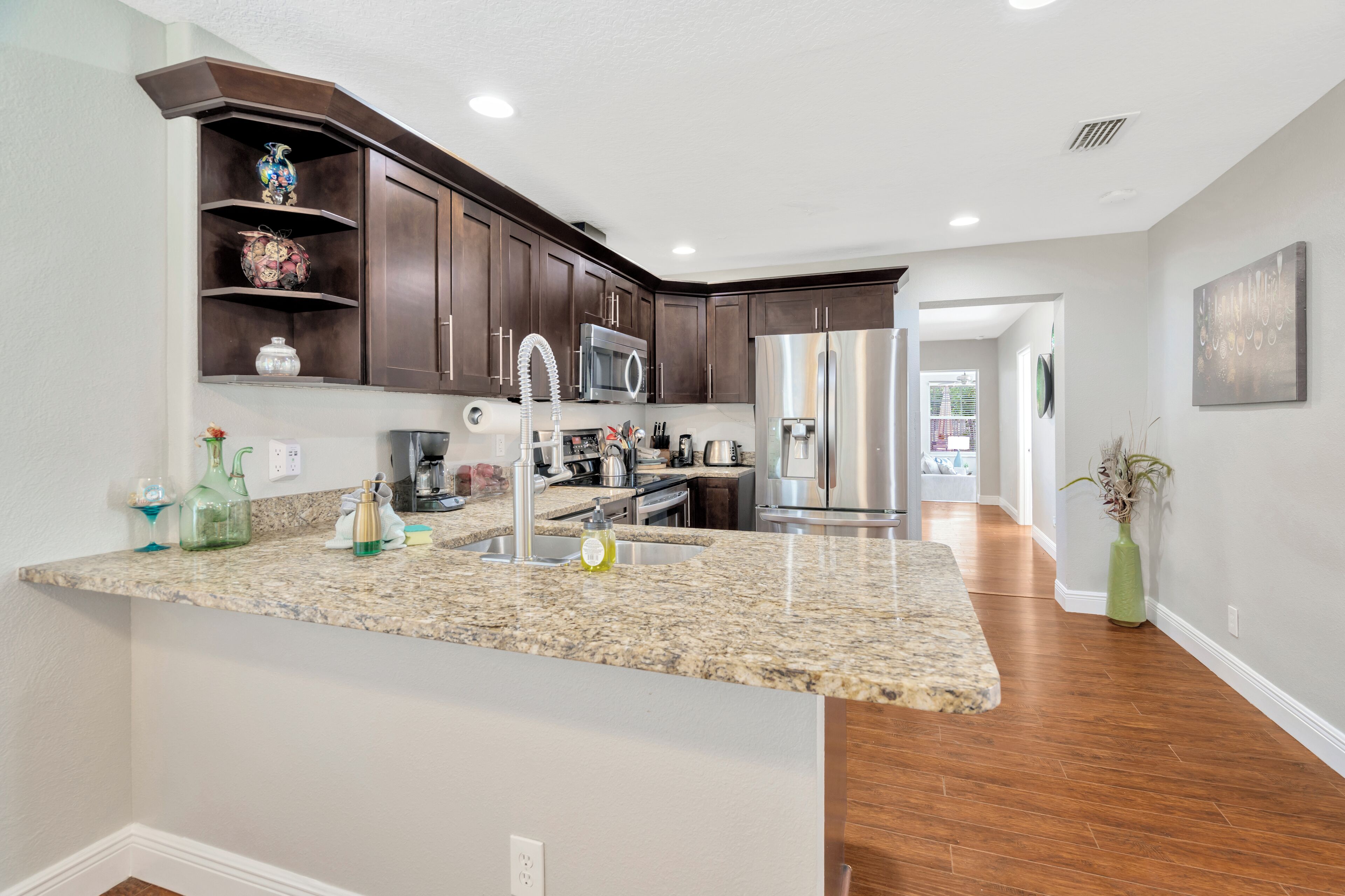 A modern kitchen with granite countertops, stainless steel appliances, and dark wood cabinetry.