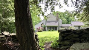 A house with a stone wall and a large tree in the foreground.