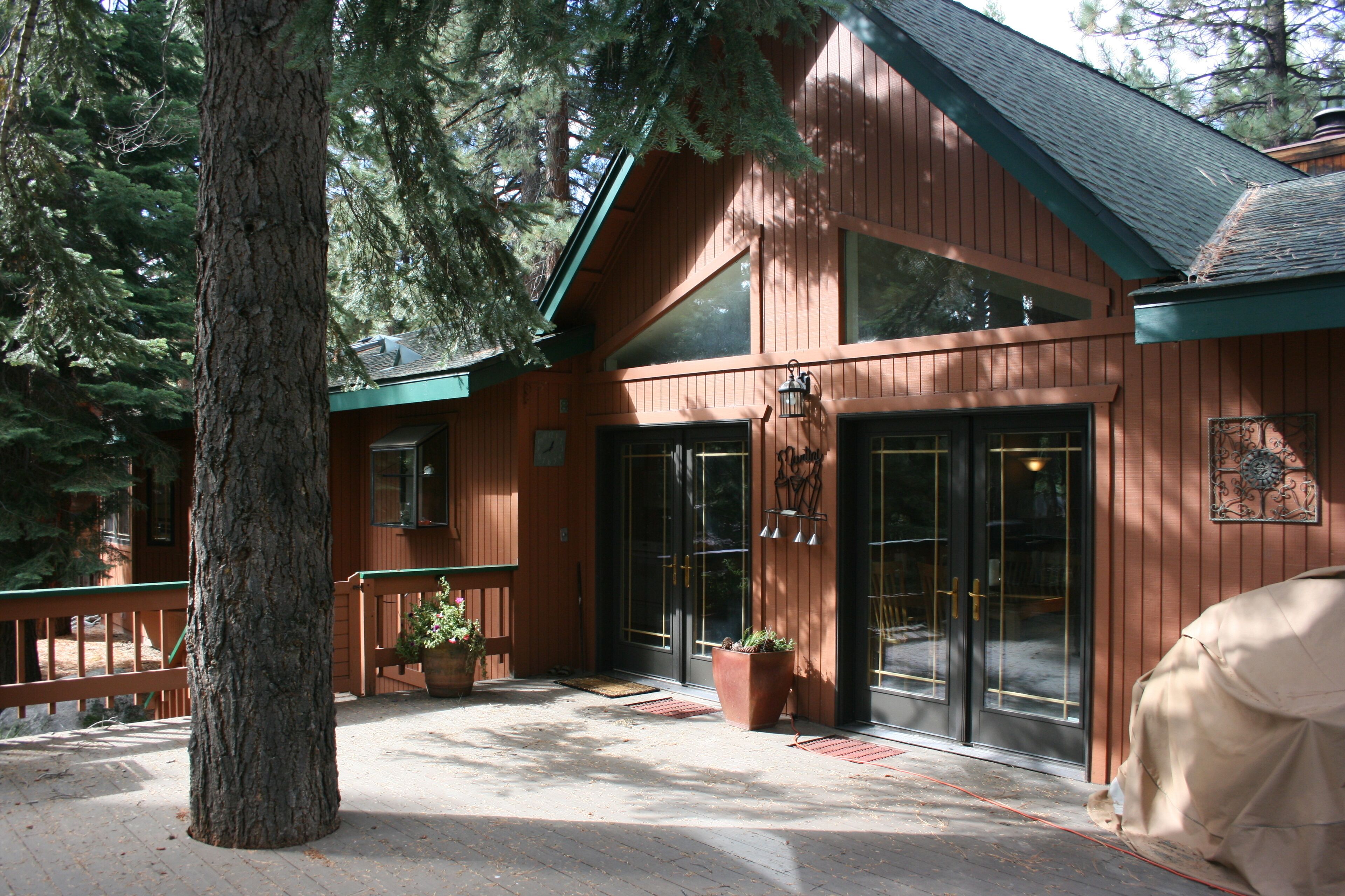 A wooden lodge with a large entrance, potted plants, and a bench.