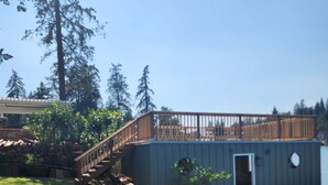 A backyard with a wooden deck, a shed, and a flower bed.