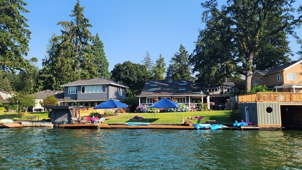 A lakeside property with a dock, a swimming pool, and a covered patio area.