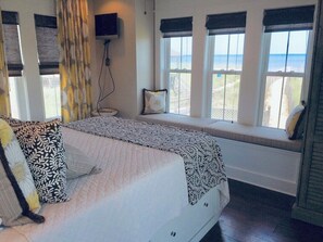 A bedroom with a bed, a window seat, and a TV mounted on the wall.