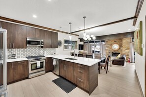 Cocina moderna con armarios de madera oscura, estufa de acero inoxidable y una isla central con pileta.
