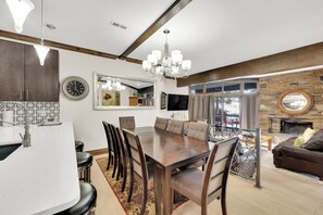 A modern dining area with a large wooden table, chairs, and a chandelier.