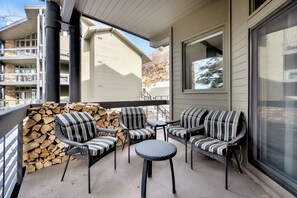 A covered outdoor seating area with wicker furniture and a stone wall.